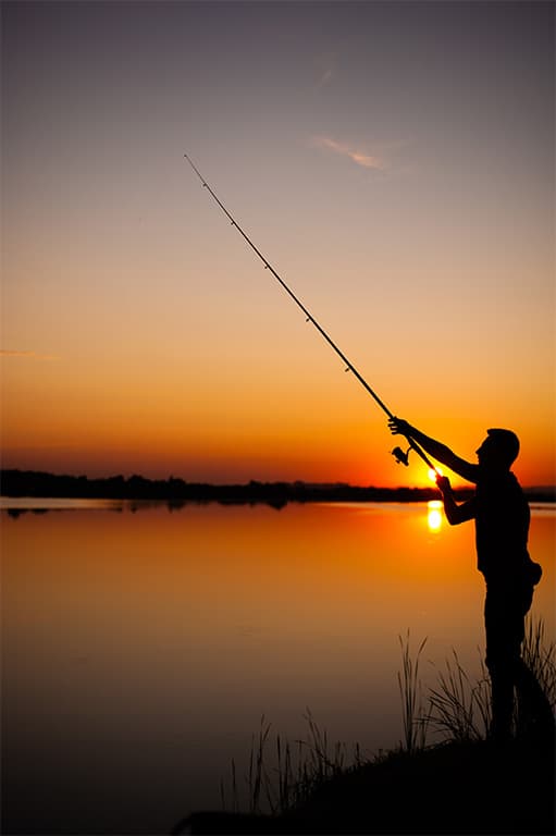 pecheur avec sa canne à pêche au coucher soleil