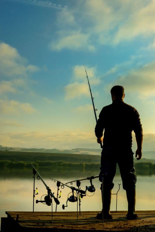 pêcheur avec sa canne à pêche au lever du jour